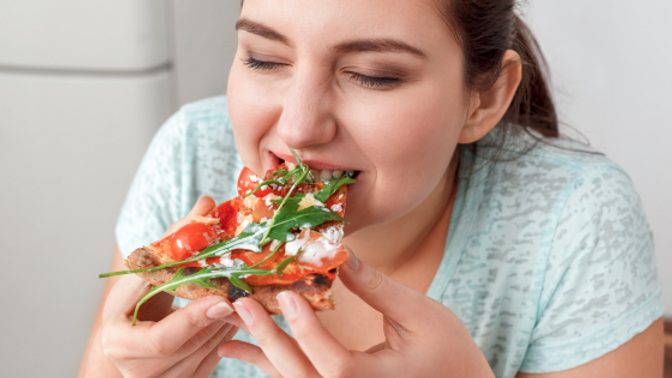 A woman eats a slice of pizza