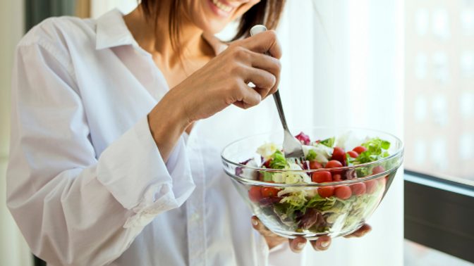 A woman eats a bowl of salad