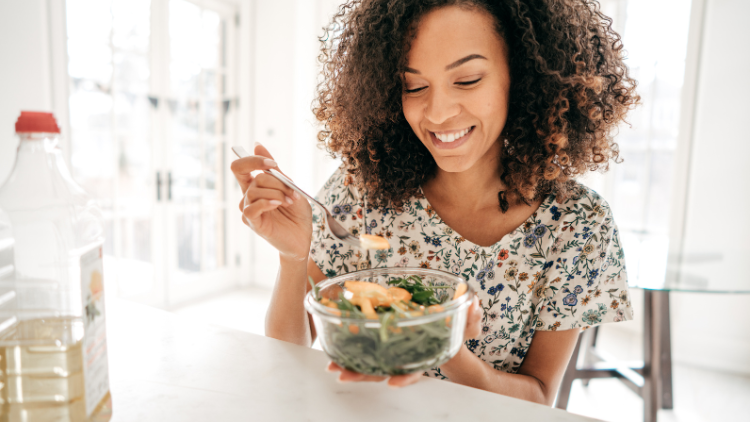 A woman eats a salad while working on intuitive eating practices