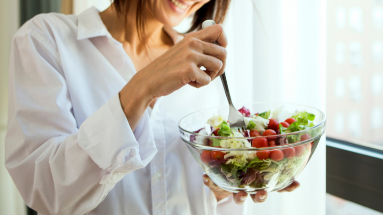 A woman eats a salad while practicing intuitive eating