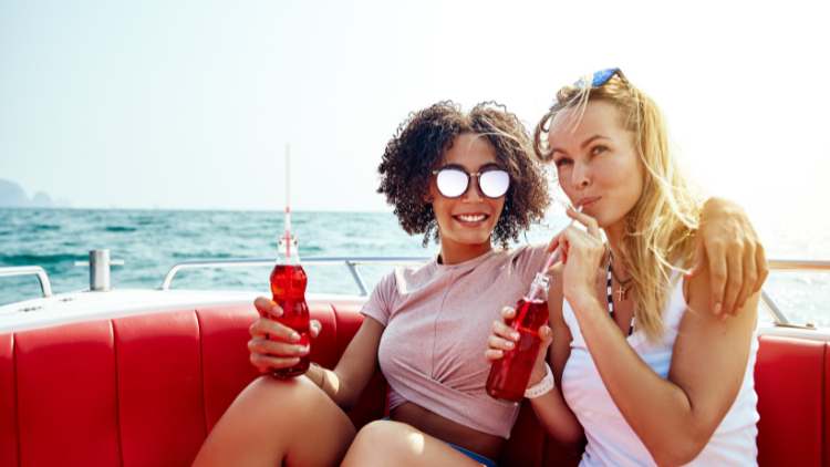 Two women practicing intuitive eating while drinking soda on a boat